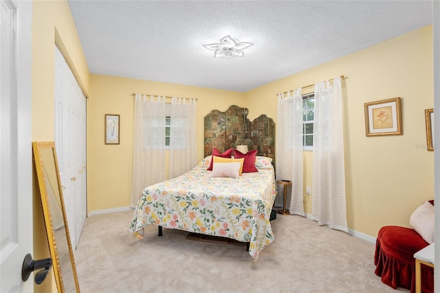 bedroom featuring light colored carpet, a textured ceiling, and a closet