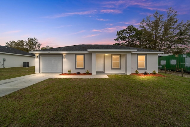 ranch-style home with a garage, a porch, a yard, and central air condition unit