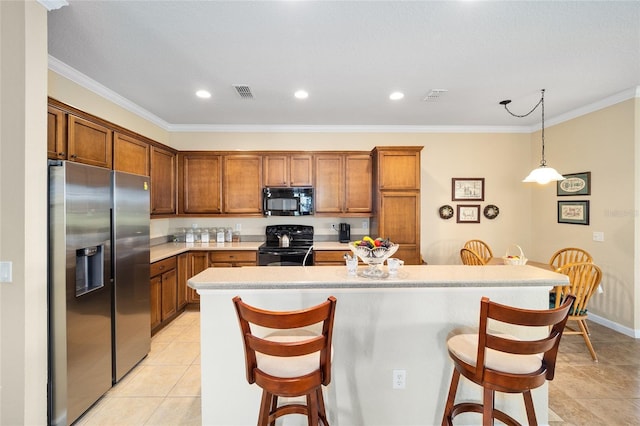 kitchen with ornamental molding, black appliances, decorative light fixtures, and a breakfast bar