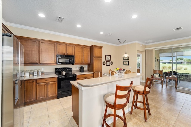 kitchen featuring black appliances, a breakfast bar area, a kitchen island with sink, crown molding, and pendant lighting