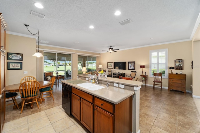 kitchen with hanging light fixtures, sink, a center island with sink, and crown molding