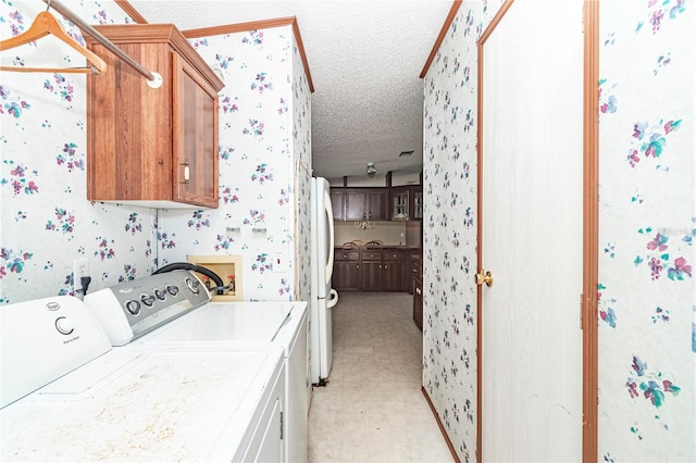 washroom with a textured ceiling, cabinets, and washing machine and clothes dryer