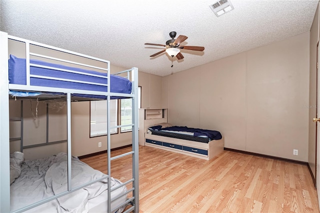 bedroom featuring ceiling fan, light hardwood / wood-style floors, and a textured ceiling