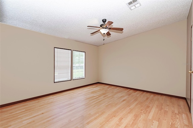 empty room with visible vents, light wood-style floors, a ceiling fan, a textured ceiling, and baseboards