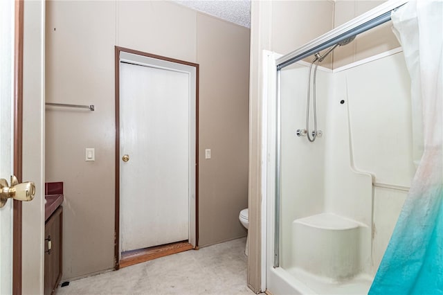 bathroom featuring toilet, a shower stall, and a textured ceiling