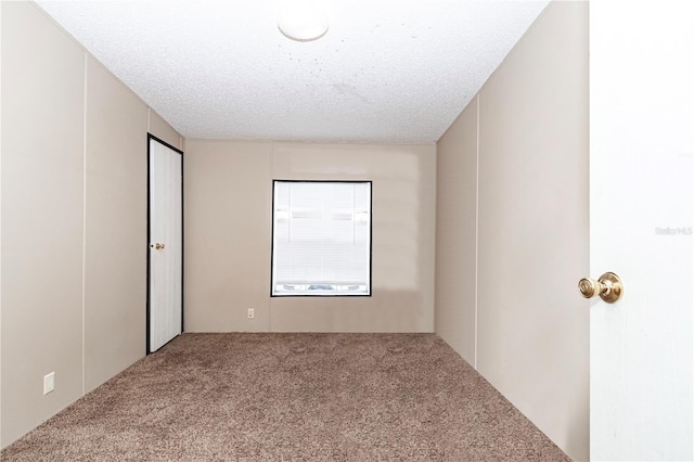 empty room featuring a textured ceiling and carpet