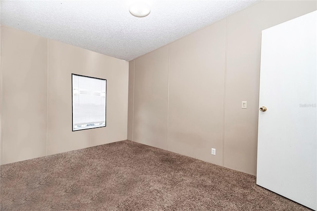 spare room with carpet, a decorative wall, and a textured ceiling