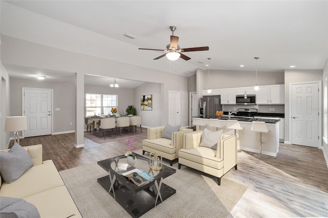 living room featuring light hardwood / wood-style floors, ceiling fan, and high vaulted ceiling