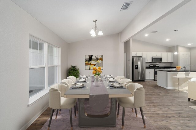 dining room featuring a notable chandelier, lofted ceiling, and hardwood / wood-style flooring