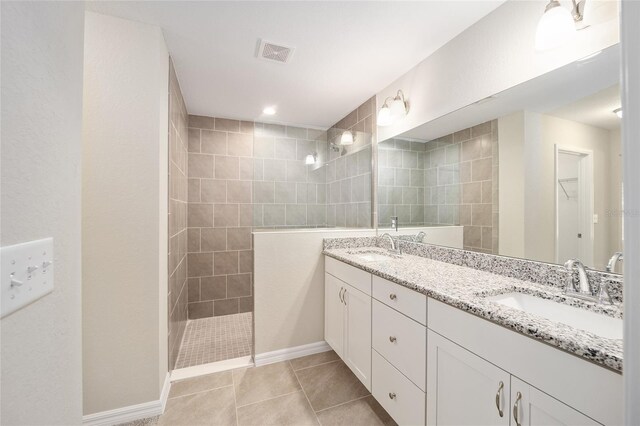 bathroom featuring dual vanity, tiled shower, and tile patterned floors