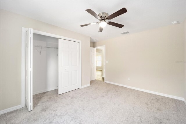 unfurnished bedroom featuring light carpet, ceiling fan, and a closet