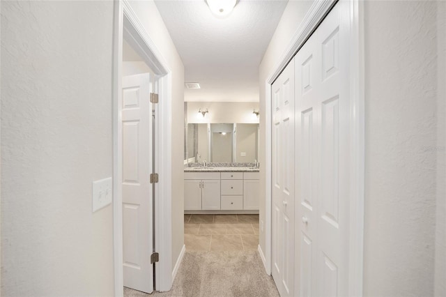 corridor featuring light colored carpet and sink