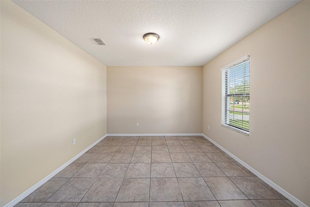 tiled spare room featuring a textured ceiling