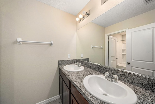 bathroom with double vanity and a textured ceiling