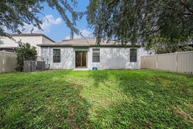 rear view of property featuring cooling unit and a yard