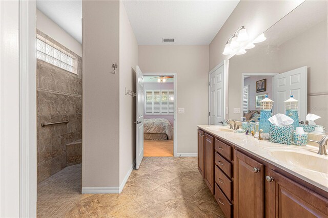 bathroom with tiled shower, vanity, and plenty of natural light