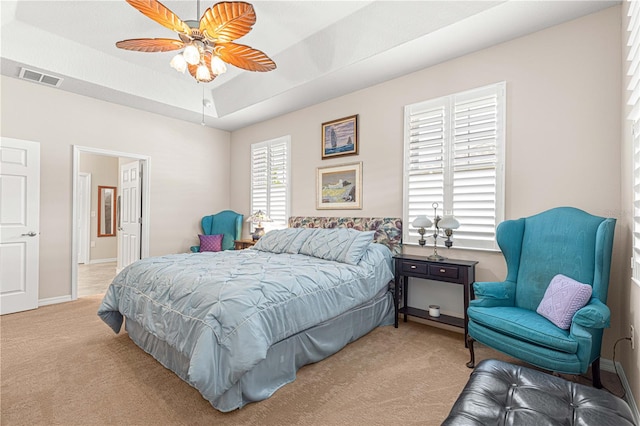 bedroom featuring light carpet, ceiling fan, and a tray ceiling