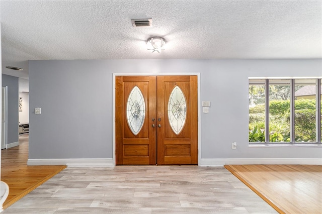 foyer with light wood-type flooring and a textured ceiling