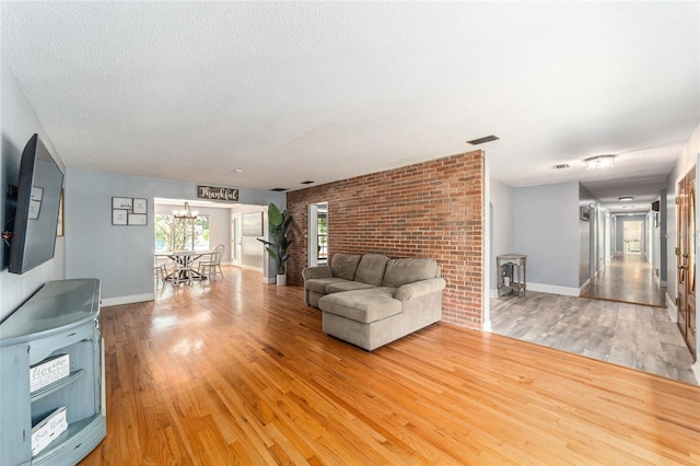 unfurnished living room with visible vents, an inviting chandelier, light wood-style floors, a wood stove, and a textured ceiling