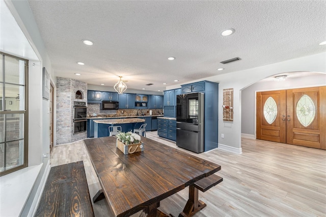 dining area with sink, a fireplace, a textured ceiling, and light hardwood / wood-style floors