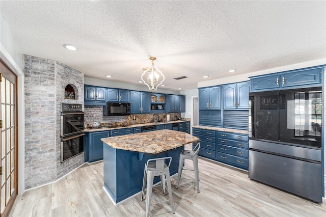 kitchen with black appliances, light wood-style floors, a sink, and blue cabinets