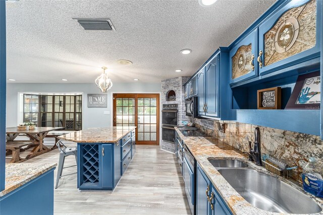 kitchen featuring light hardwood / wood-style floors, blue cabinets, sink, and light stone counters