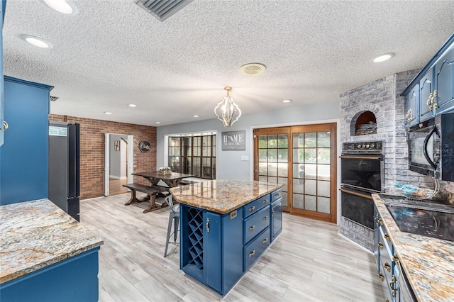 kitchen featuring a textured ceiling, blue cabinetry, and light wood-type flooring