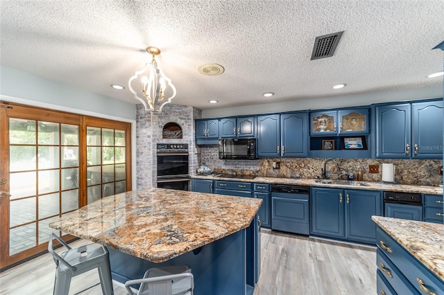 kitchen featuring decorative backsplash, sink, blue cabinetry, black appliances, and light wood-type flooring