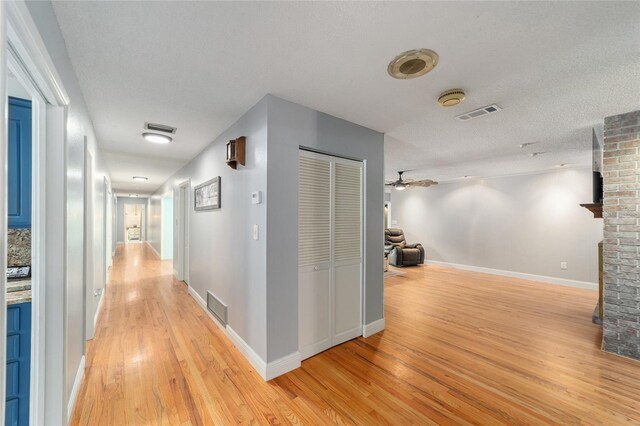 hallway featuring a textured ceiling and light hardwood / wood-style floors