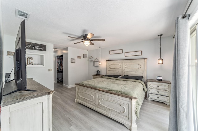 bedroom featuring visible vents, light wood-style floors, a ceiling fan, a textured ceiling, and baseboards