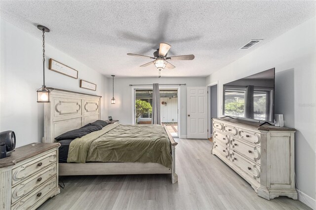 bedroom with light wood-type flooring, ceiling fan, and a textured ceiling