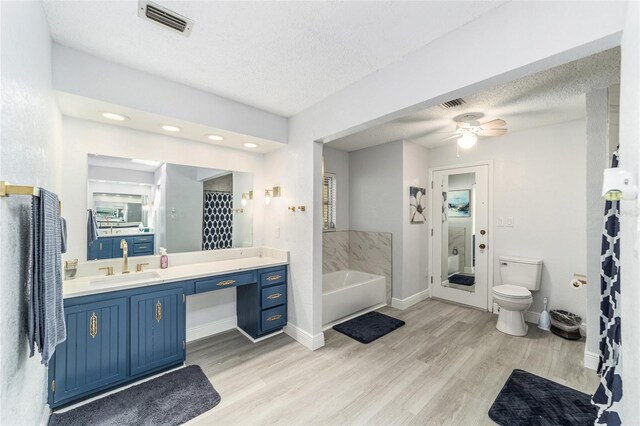 full bathroom with hardwood / wood-style floors, vanity, a textured ceiling, ceiling fan, and toilet