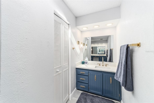 bathroom with tile patterned flooring, a textured ceiling, and vanity