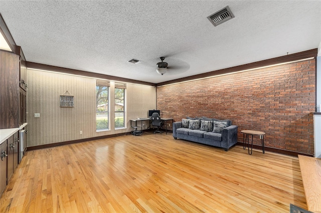 unfurnished living room with a textured ceiling, light wood-style flooring, visible vents, and a ceiling fan