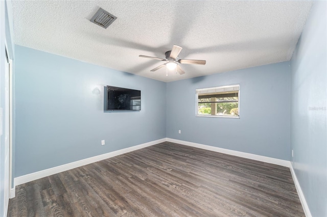 spare room with ceiling fan, a textured ceiling, visible vents, baseboards, and dark wood finished floors