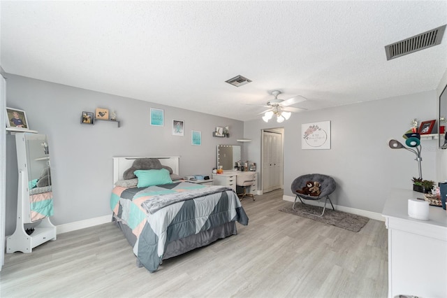 bedroom featuring ceiling fan, light hardwood / wood-style flooring, a textured ceiling, and a closet