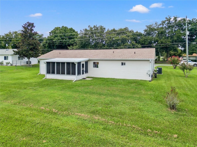 back of property with central air condition unit, a lawn, and a sunroom