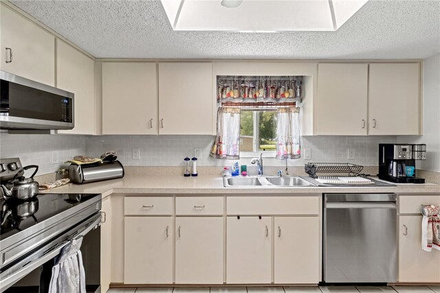 kitchen with sink, stainless steel appliances, a textured ceiling, and decorative backsplash