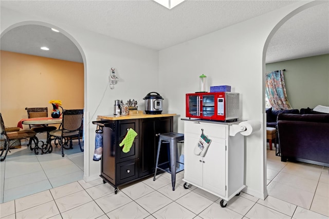 interior space with wooden counters, a textured ceiling, and light tile patterned flooring