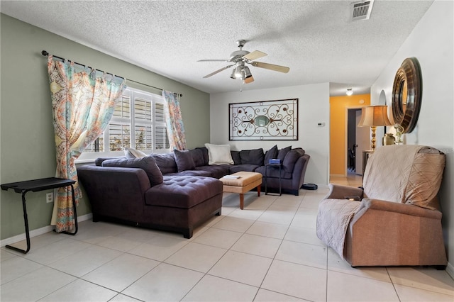 living room with a textured ceiling, ceiling fan, and light tile patterned floors