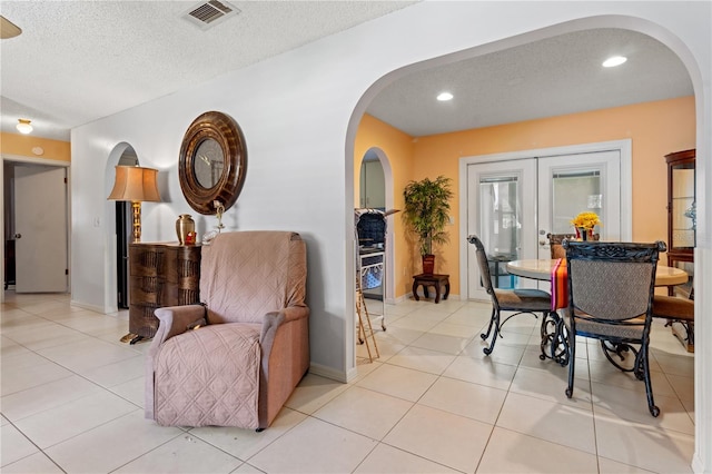 tiled dining area with french doors and a textured ceiling