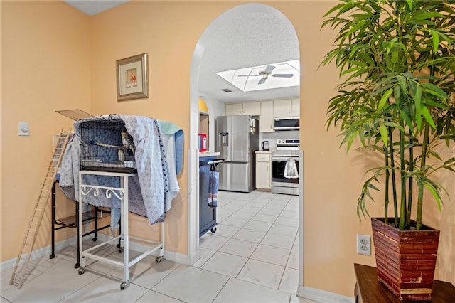 kitchen featuring white cabinets, stainless steel appliances, ceiling fan, and light tile patterned floors