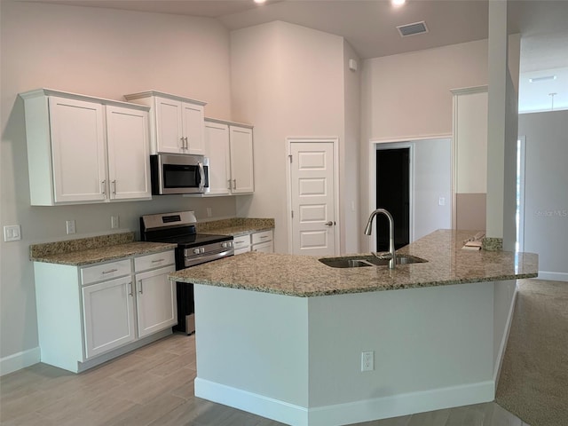 kitchen featuring light stone counters, sink, stainless steel appliances, and white cabinets