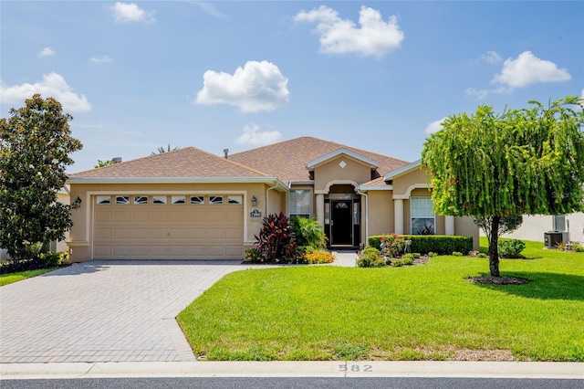 single story home featuring a garage, a front lawn, and central air condition unit