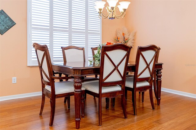 dining area with hardwood / wood-style flooring and an inviting chandelier