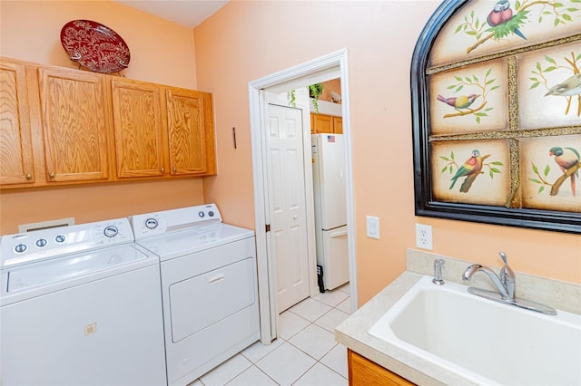 laundry area with cabinets, light tile patterned floors, sink, and washing machine and clothes dryer