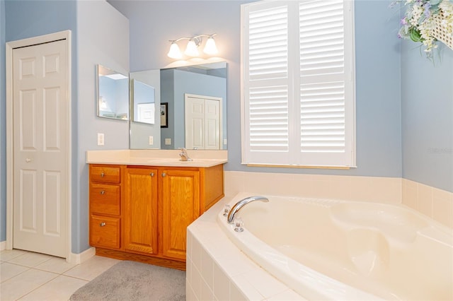 bathroom featuring a relaxing tiled tub, vanity, and tile patterned flooring