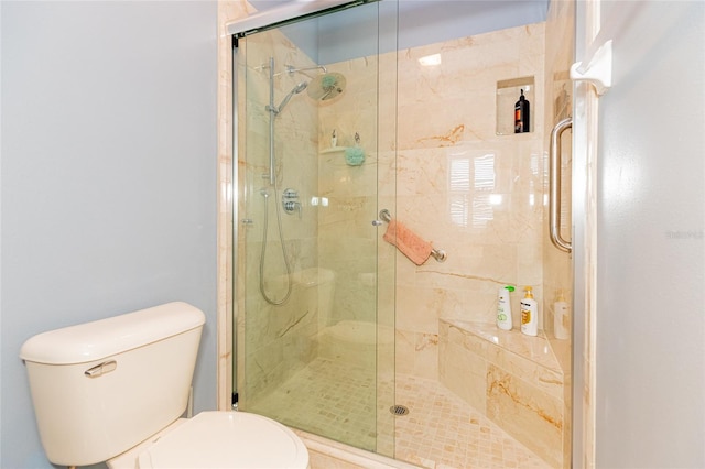 bathroom featuring toilet and a shower with shower door