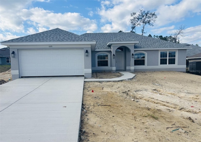 single story home featuring a garage, roof with shingles, concrete driveway, and stucco siding