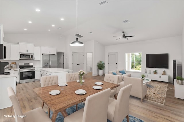 dining space featuring ceiling fan, high vaulted ceiling, and light wood-type flooring